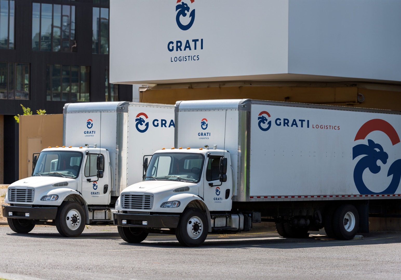 Three white trucks parked in front of a building.