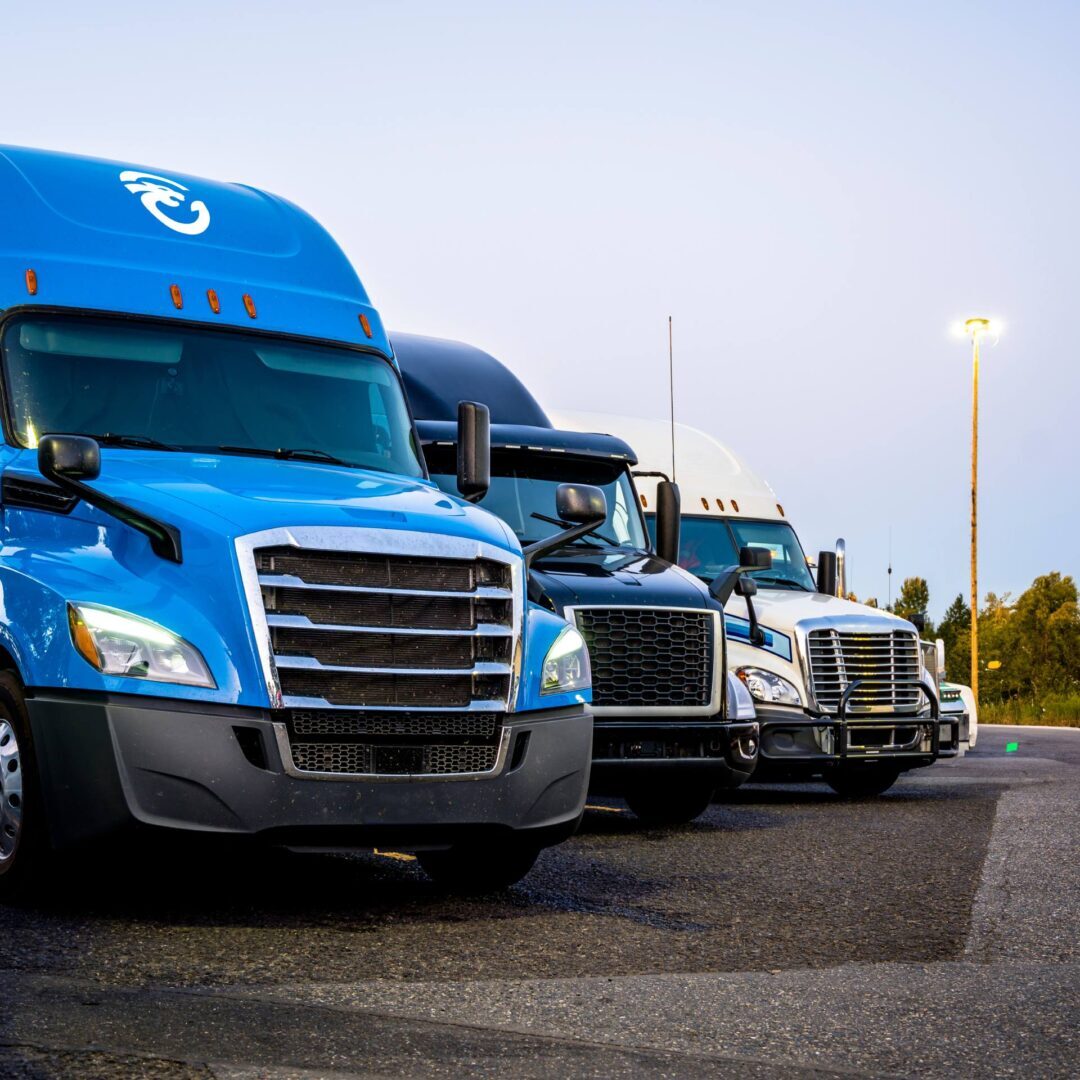 A row of blue semi trucks parked in a parking lot.