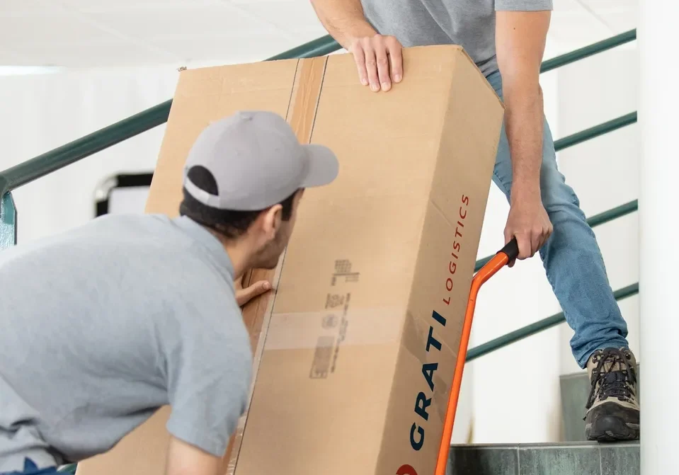 Two men moving a box down the stairs.